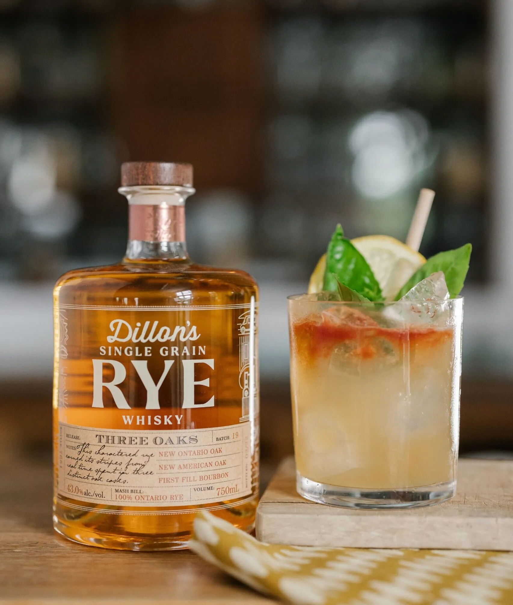 A bottle of rye whisky alongside a cocktail